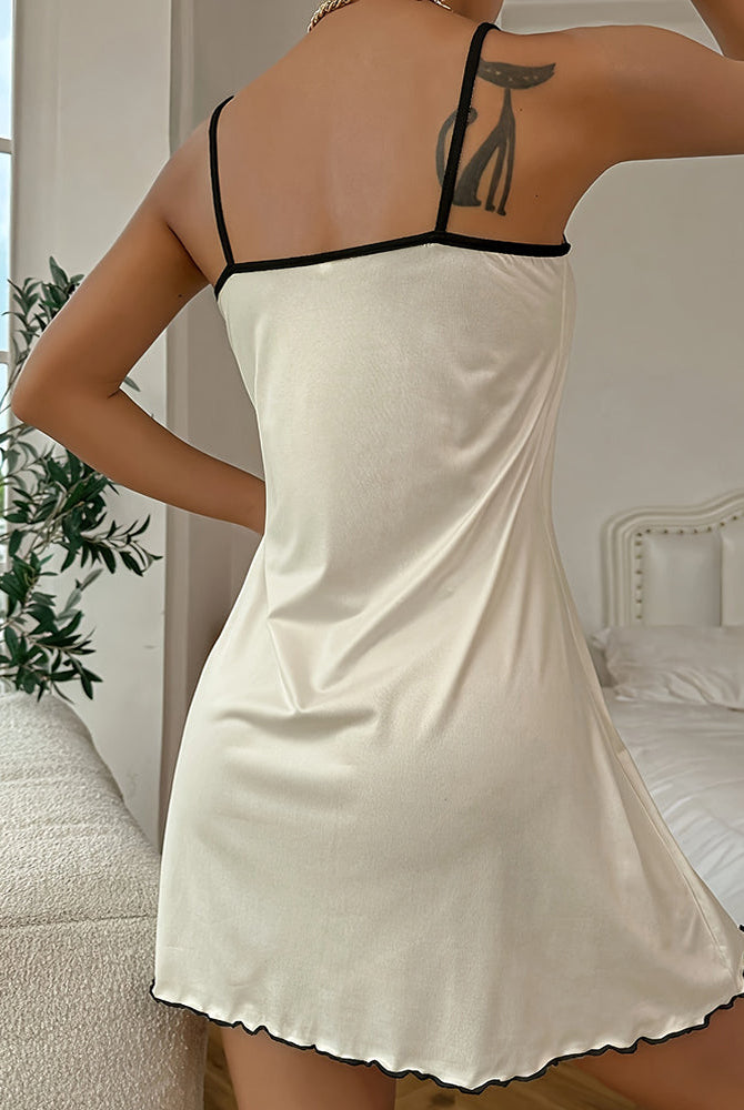 Cream mini slip dress with thin black spaghetti straps and scalloped hem