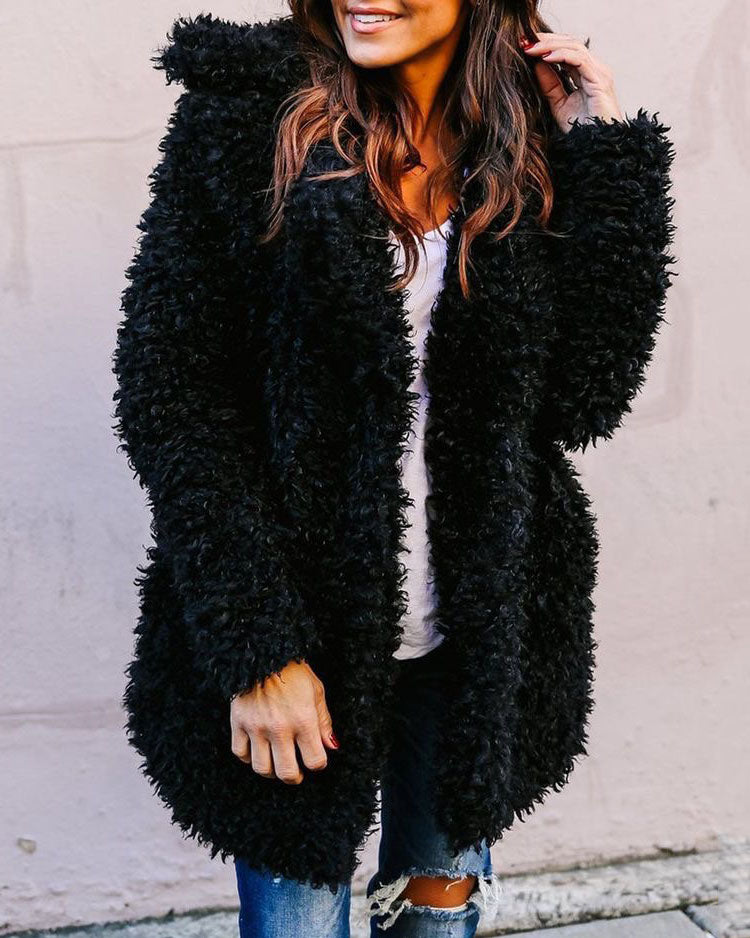 Oversized black faux fur coat. Soft, textured material, casual style, button detail.