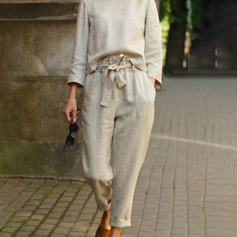 Beige two-piece pants set, perfect for vacation and leisure. Features a tie belt and long sleeves.