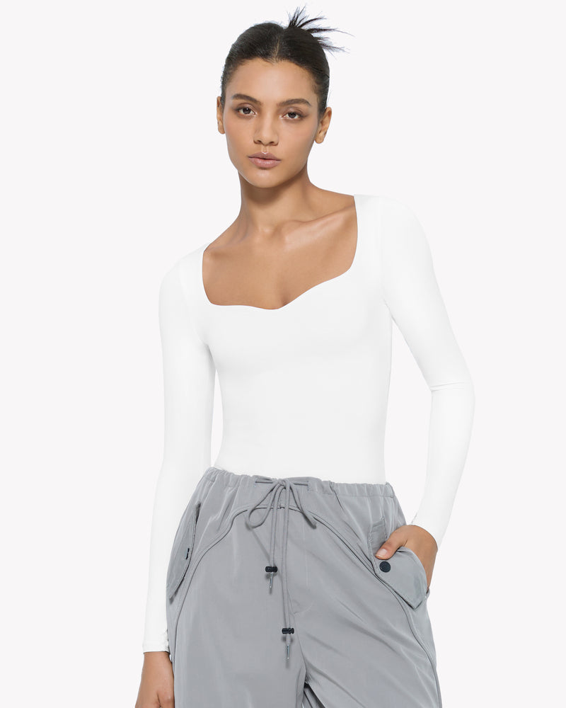White sweetheart neckline long sleeve bodysuit shapewear, model wearing gray pants, premium comfort