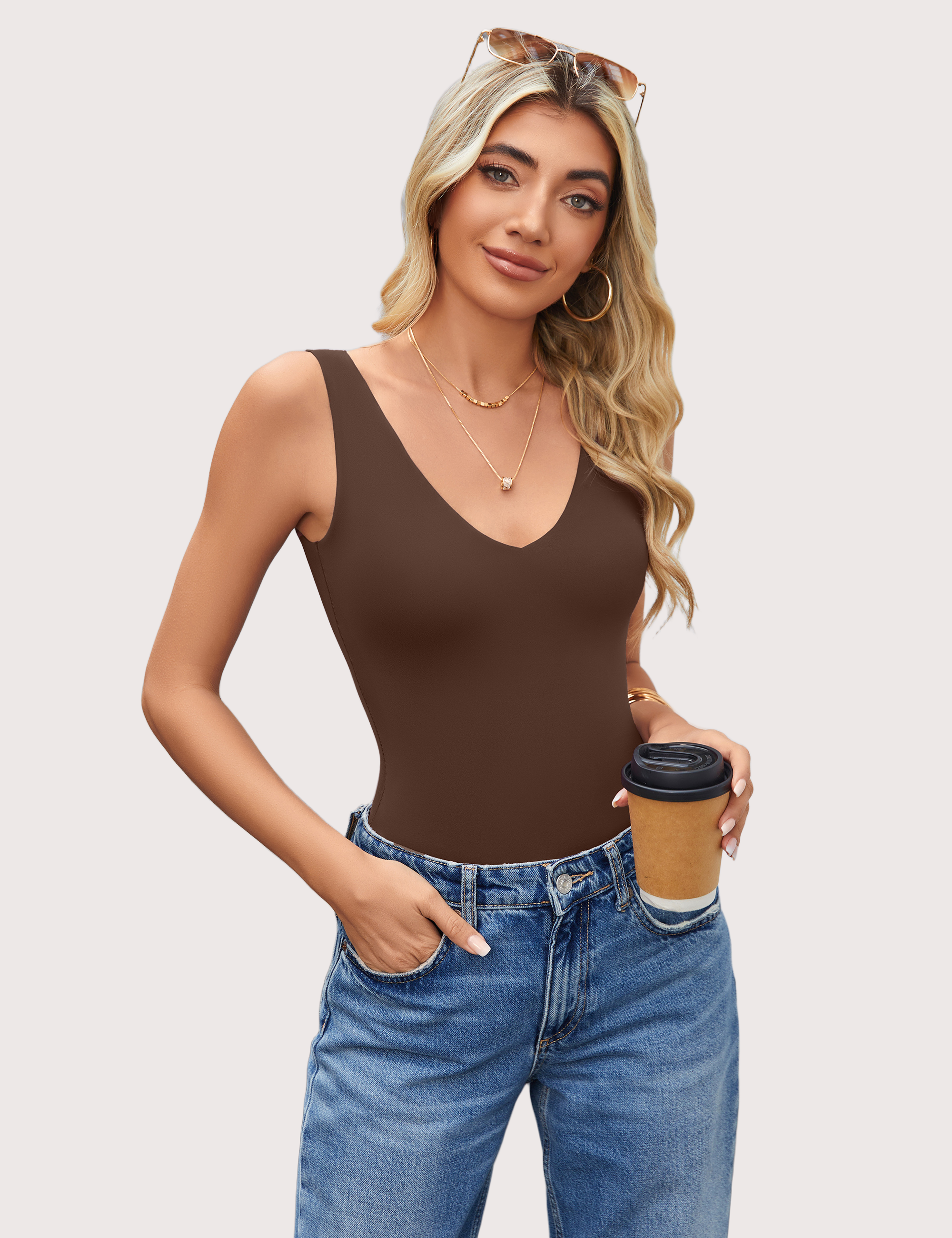 Brown bodysuit leotard with plunging V-neck and open back, paired with blue jeans.