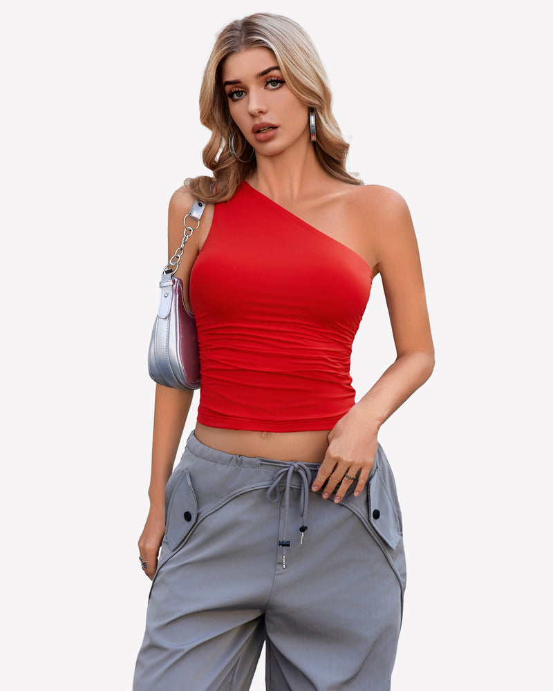 Red one-shoulder crop top with ruched detail, gray cargo pants. Stylish outfit.