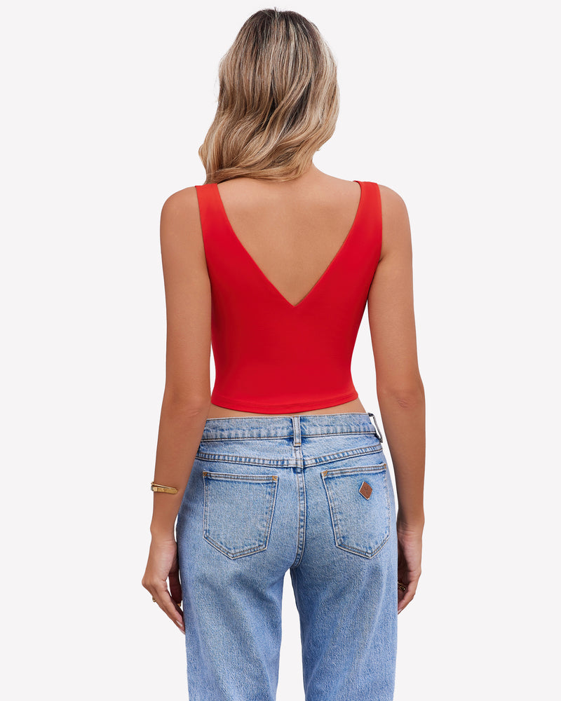 Red crop plunge tank top with V-neck and wide straps, paired with light blue jeans, a stylish look.
