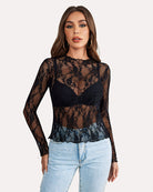 Back view of sheer white floral lace blouse with long sleeves, paired with black jeans.