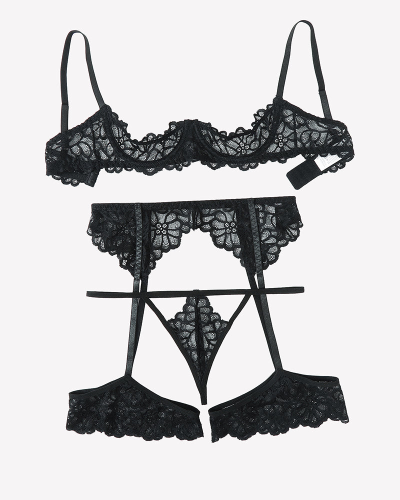 Black lace lingerie set flat lay: balconette bra, garter belt, thong, thigh garters