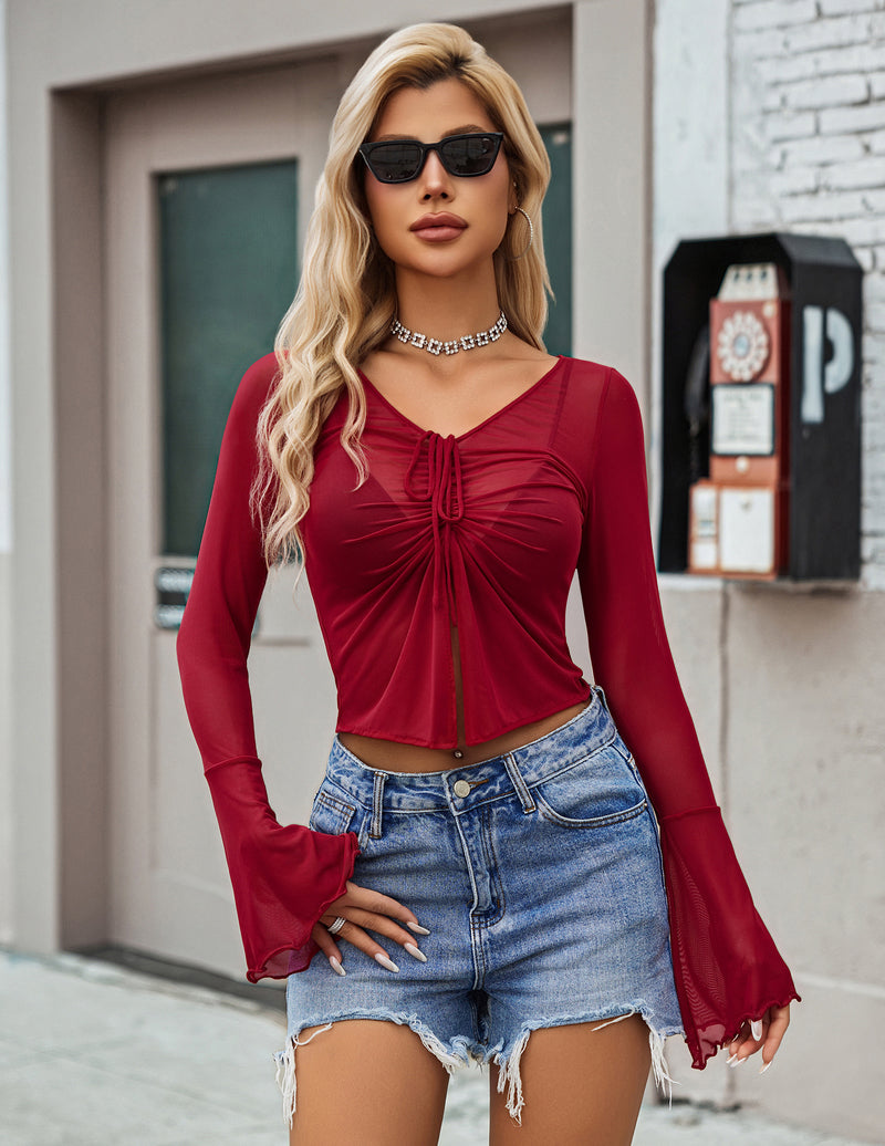 Red crop top modeled with a ruched tie front, V-neck, and flared sleeves