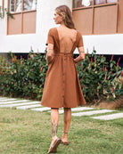 Brown open back midi dress with button details, perfect for a stylish and comfortable look.