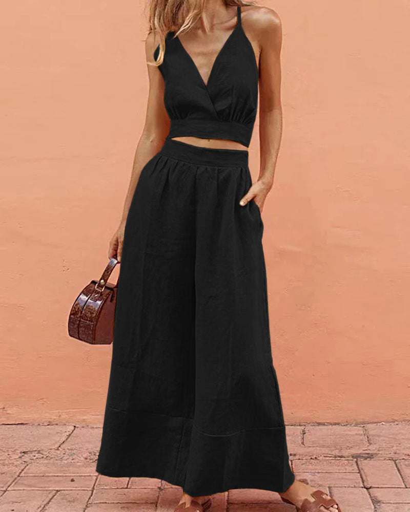 Black crop top and wide-leg pants set, vacation style. Features V-neck and spaghetti straps.