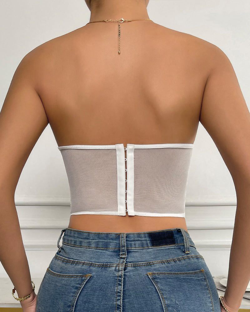 White strapless mesh bustier top with boning, offering support and shaping, paired with denim jeans.