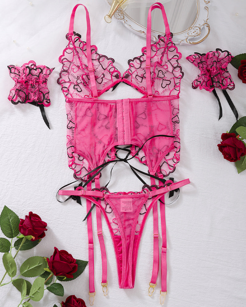 Heart embroidered pink lingerie set with strappy bra, corset, thong, and cuffs. Sexy lingerie.