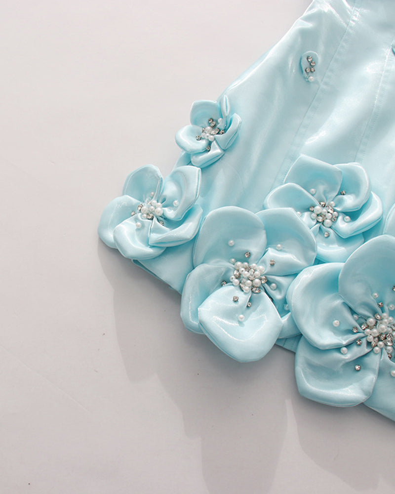 Close-up of sky blue 3D floral rosette appliques with rhinestone and pearl details.