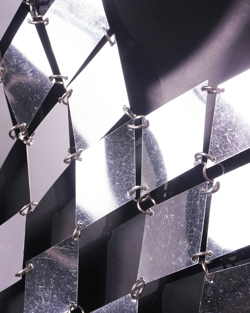 Close-up of silver metal chain-link pattern on a dark backing panel.