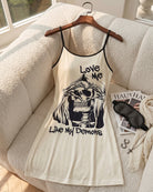 Cream mini slip dress on hanger with spaghetti straps and skull graphic front