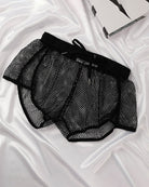 Black open mesh drawstring shorts with elastic waistband and drawstring ties.