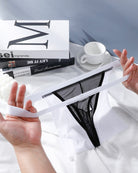 Black sheer g-string thong with elastic waistband, shown with white satin pouch