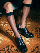 Sheer mid-calf dress socks with dark blue band at top, worn with black lace shoes