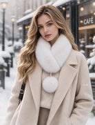 White faux fur collar scarf with a single pom-pom, worn over a coat.