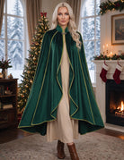 Green velvet cloak cape with gold trim and flowing cape panels worn over cream dress